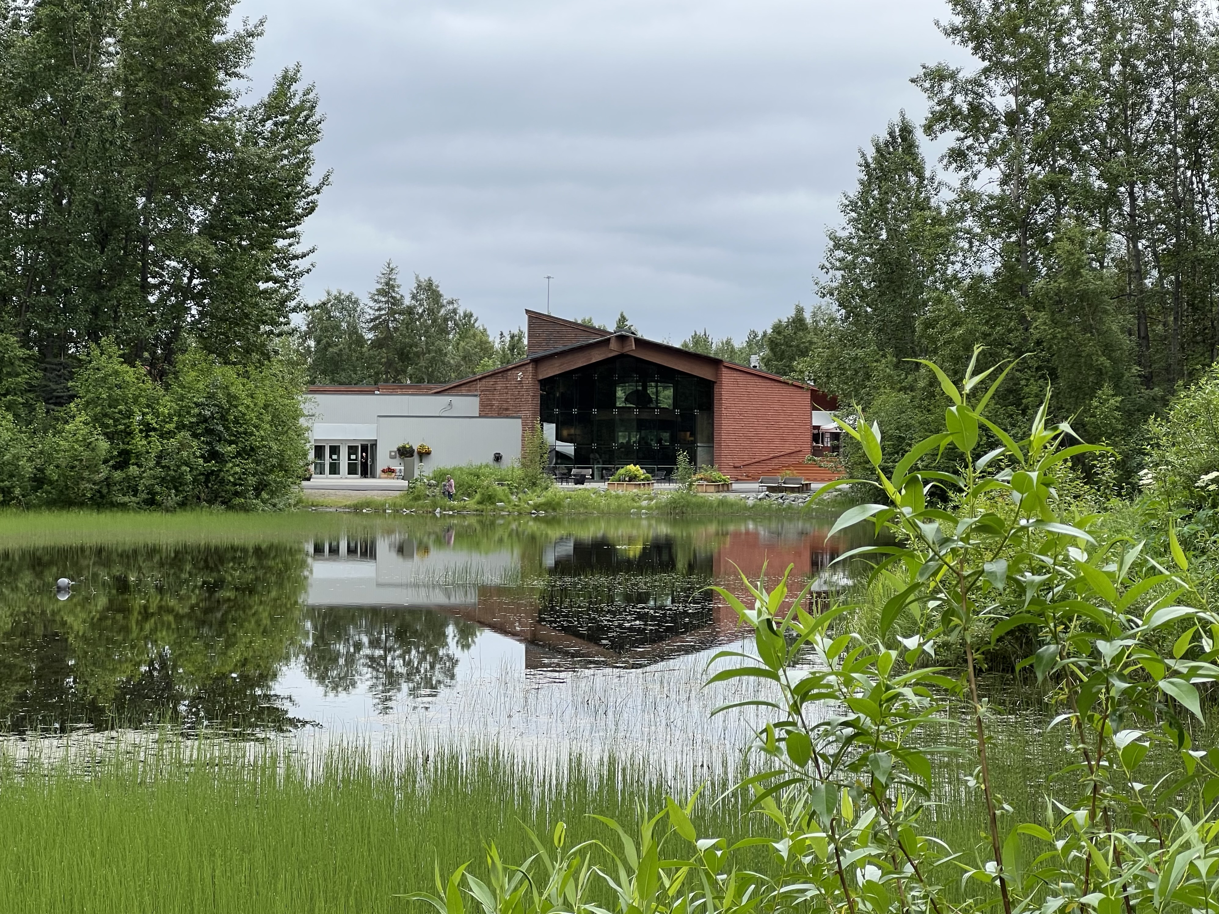 An angled building with a sparkling pond in the foreground