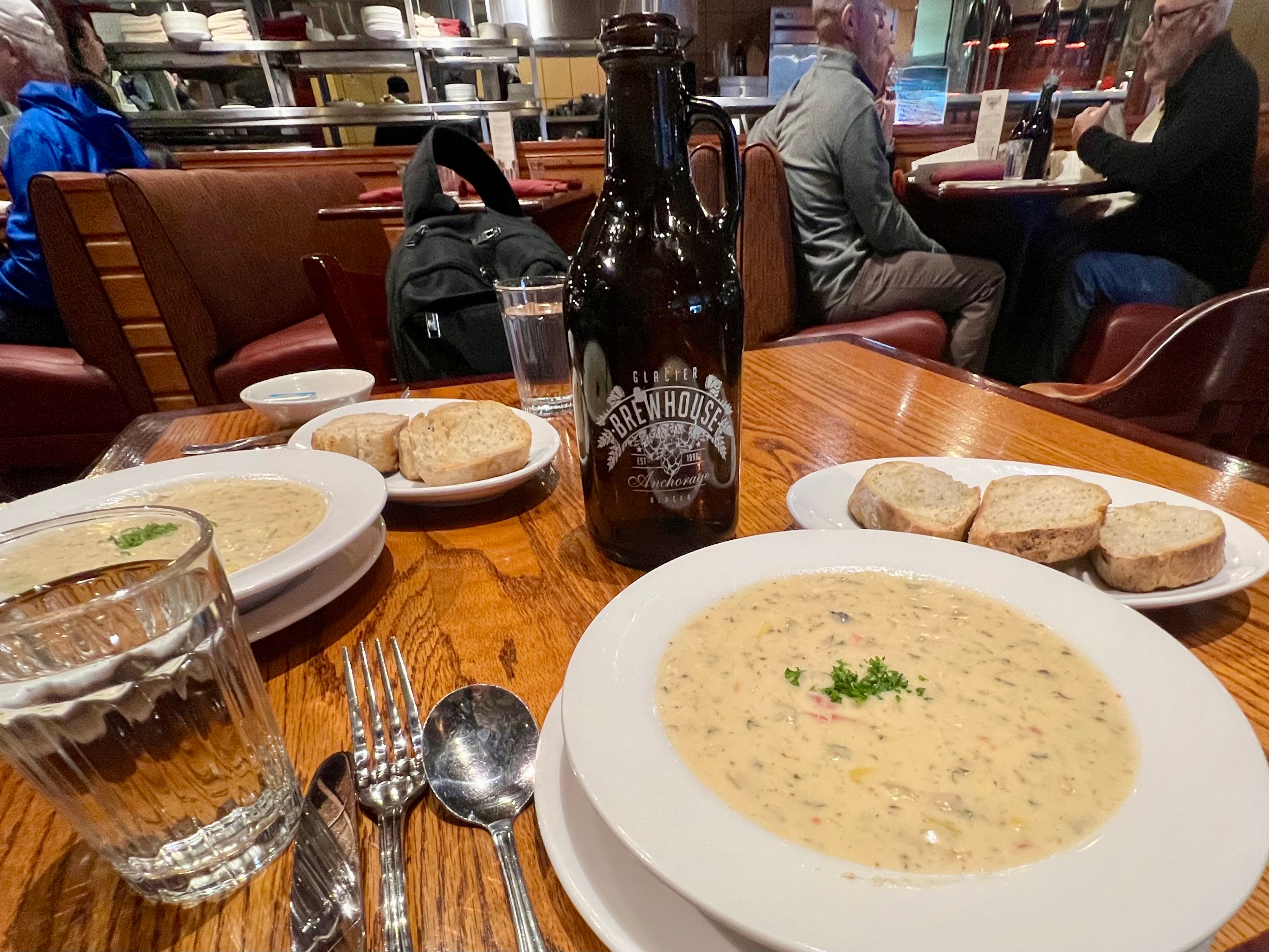 A bowl of creamy seafood chowder and a brown bottle of beer