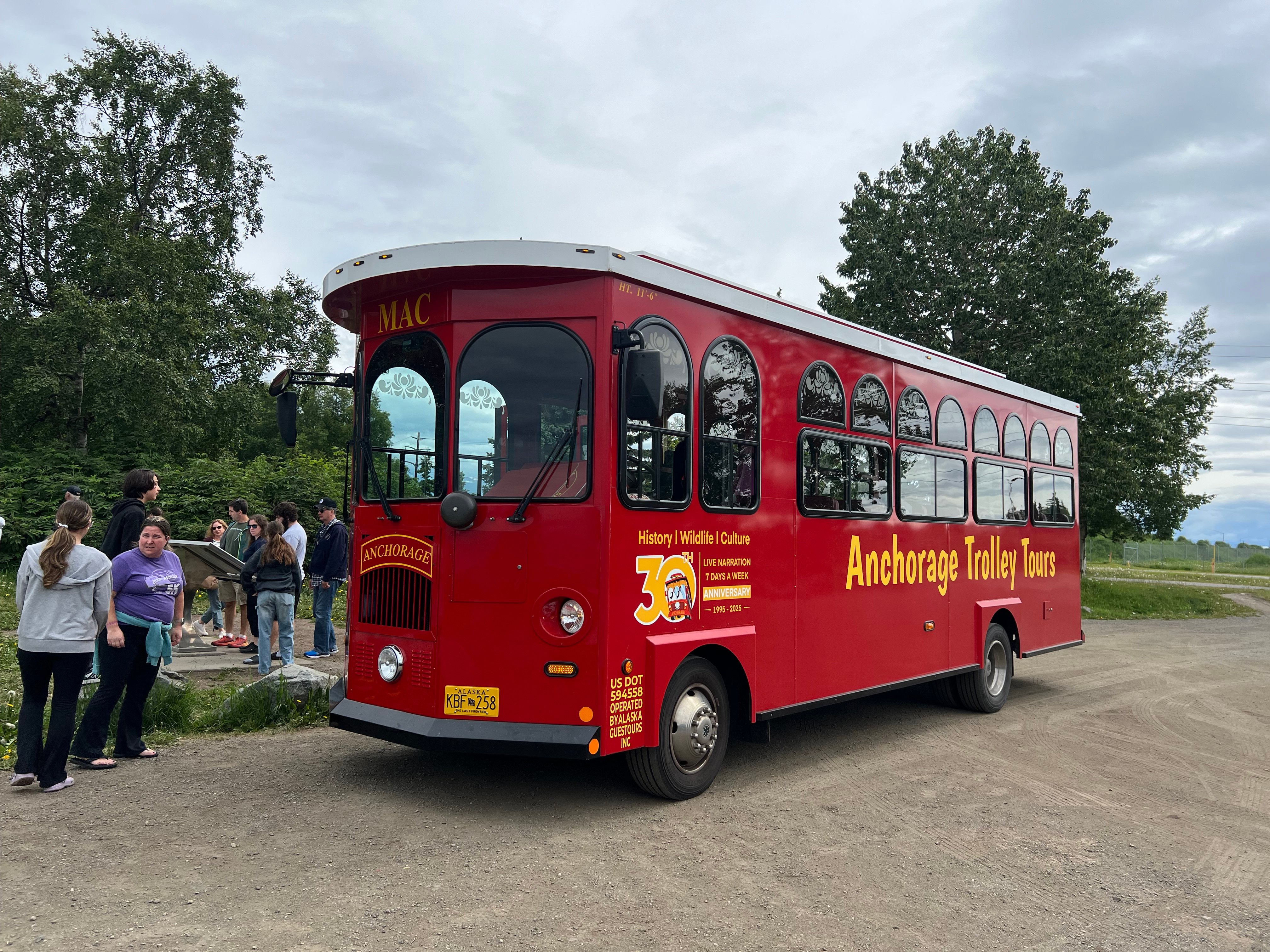 A red trolley parked in front of a natural area