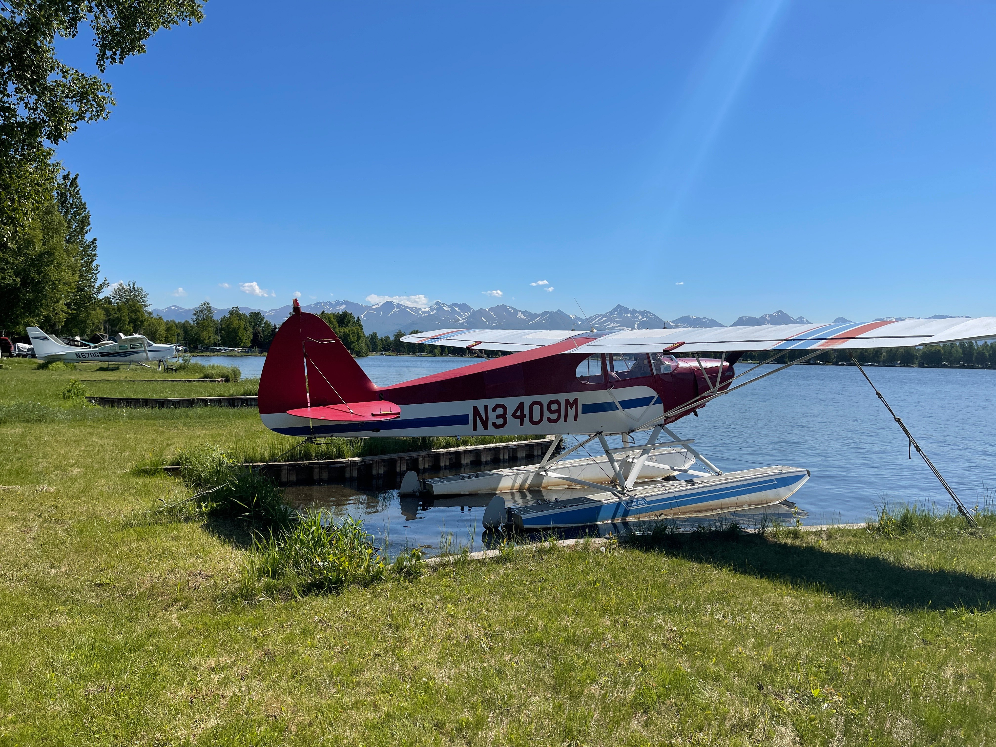 A red and white seaplane sits on the edge of the water