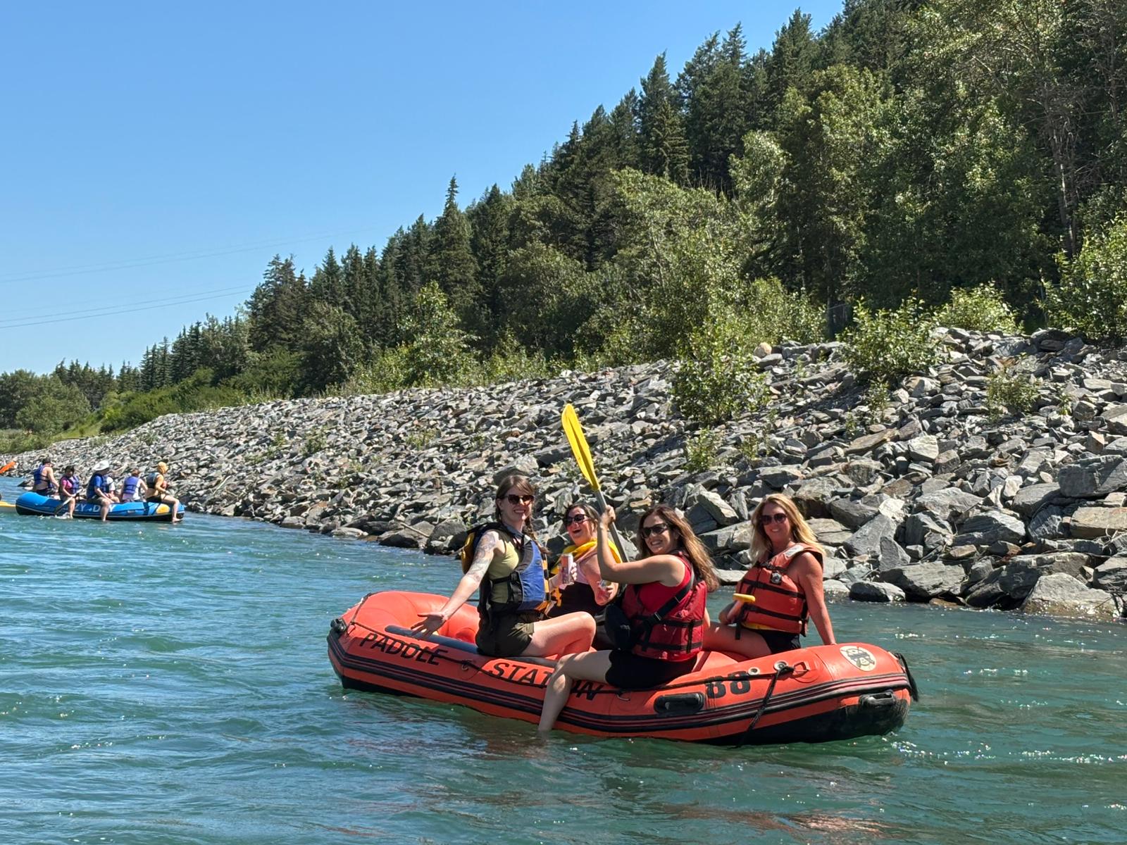 A group of four women on an orange raft floating the Bow River in Calgary