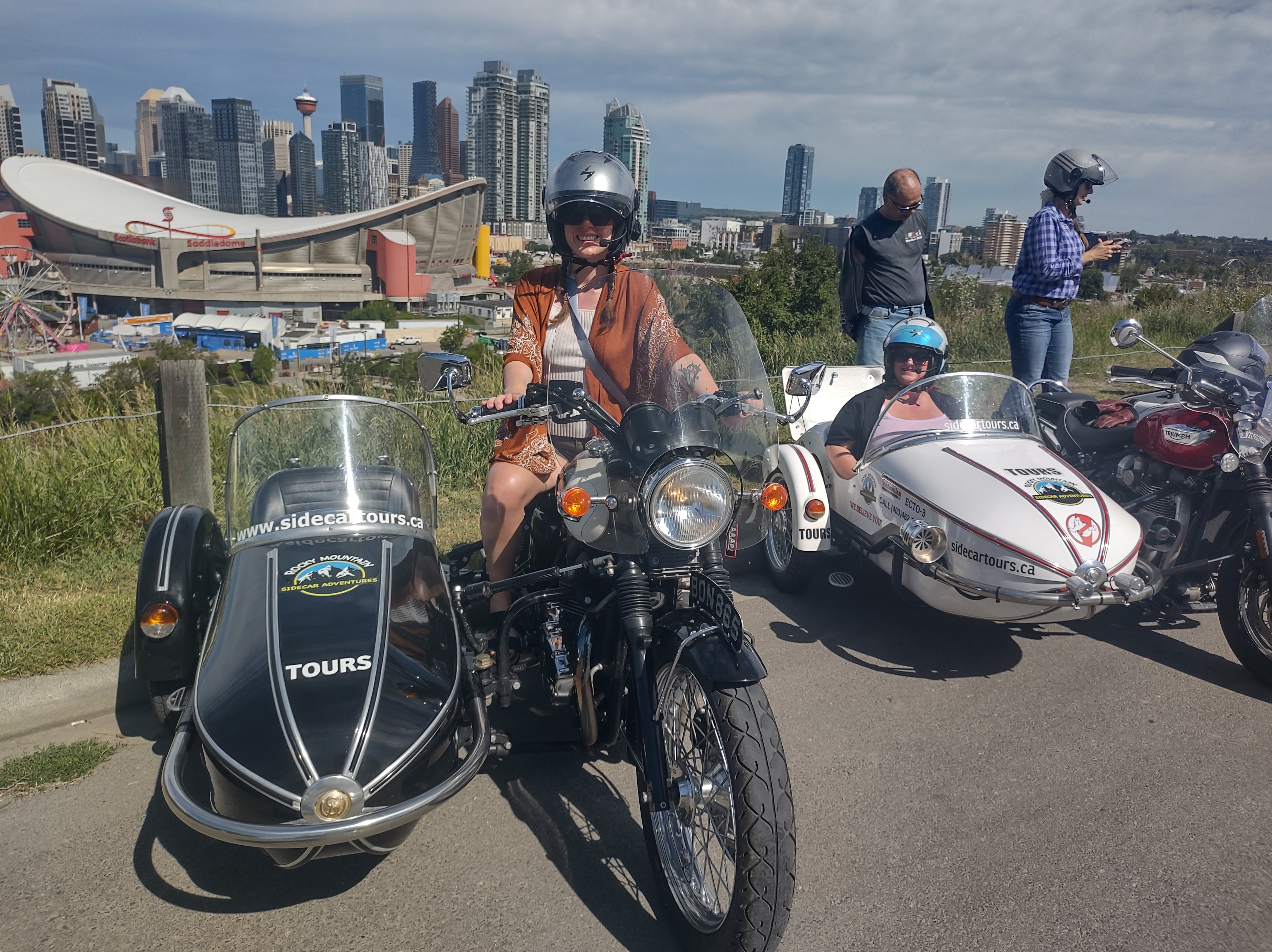 A girl posing on a motorcycle with a sidecar attached to it in front of the Calgary Stampede grounds