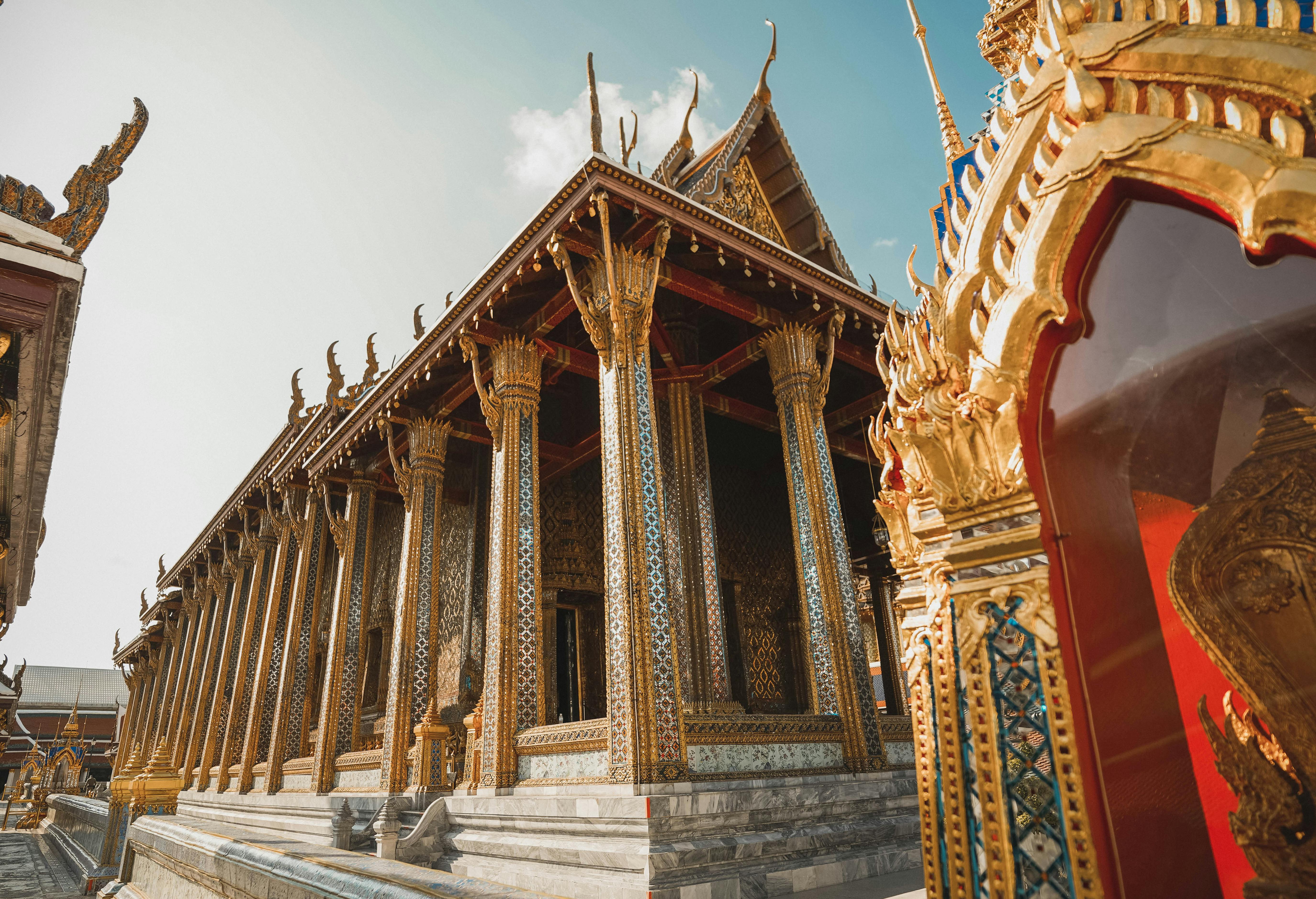 A temple with golden, accented columns and a vibrant red door