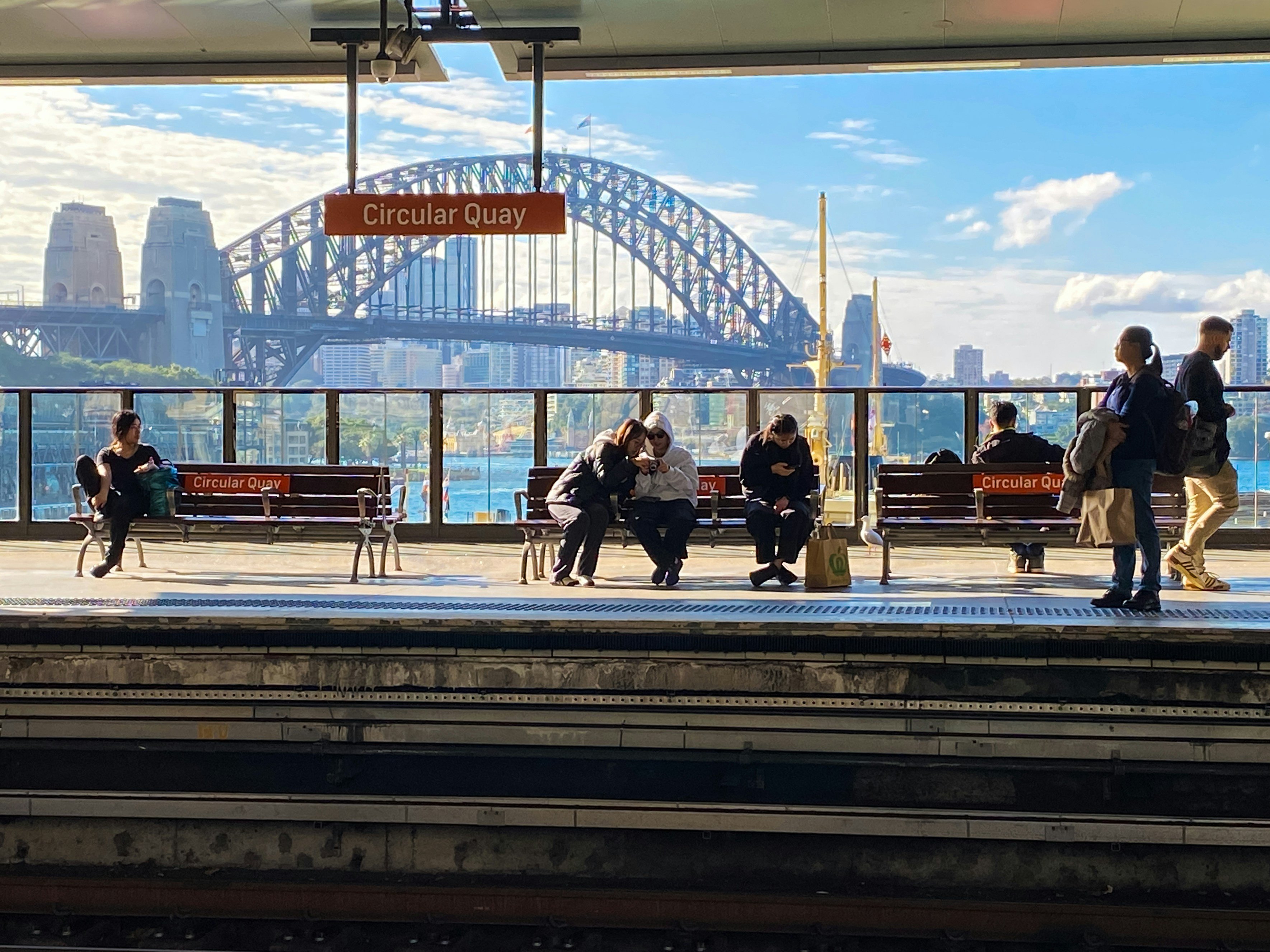 People sit on benches waiting for the train in Sydney, Australia