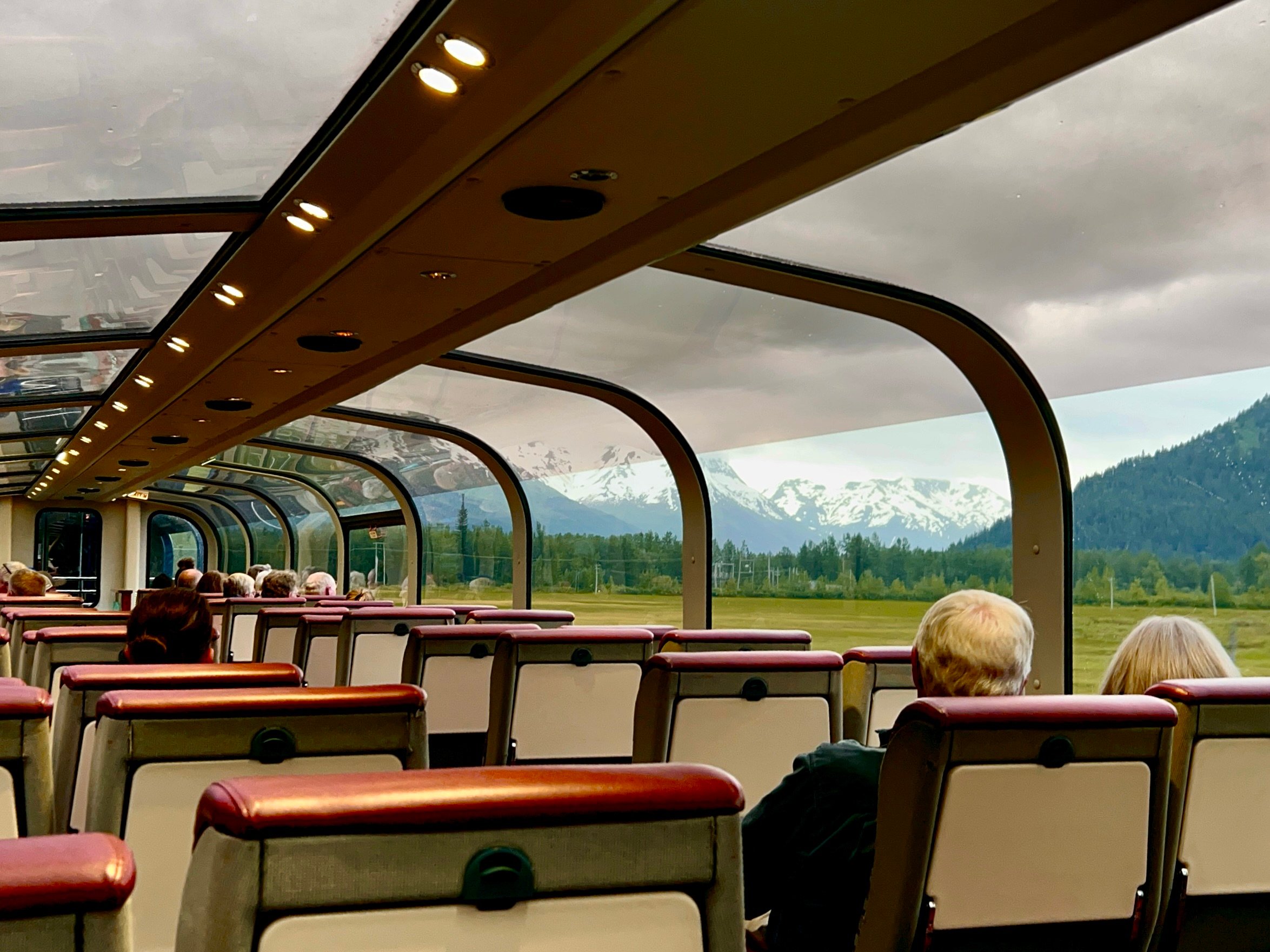 A group of people sitting on a train with a domed glass roof