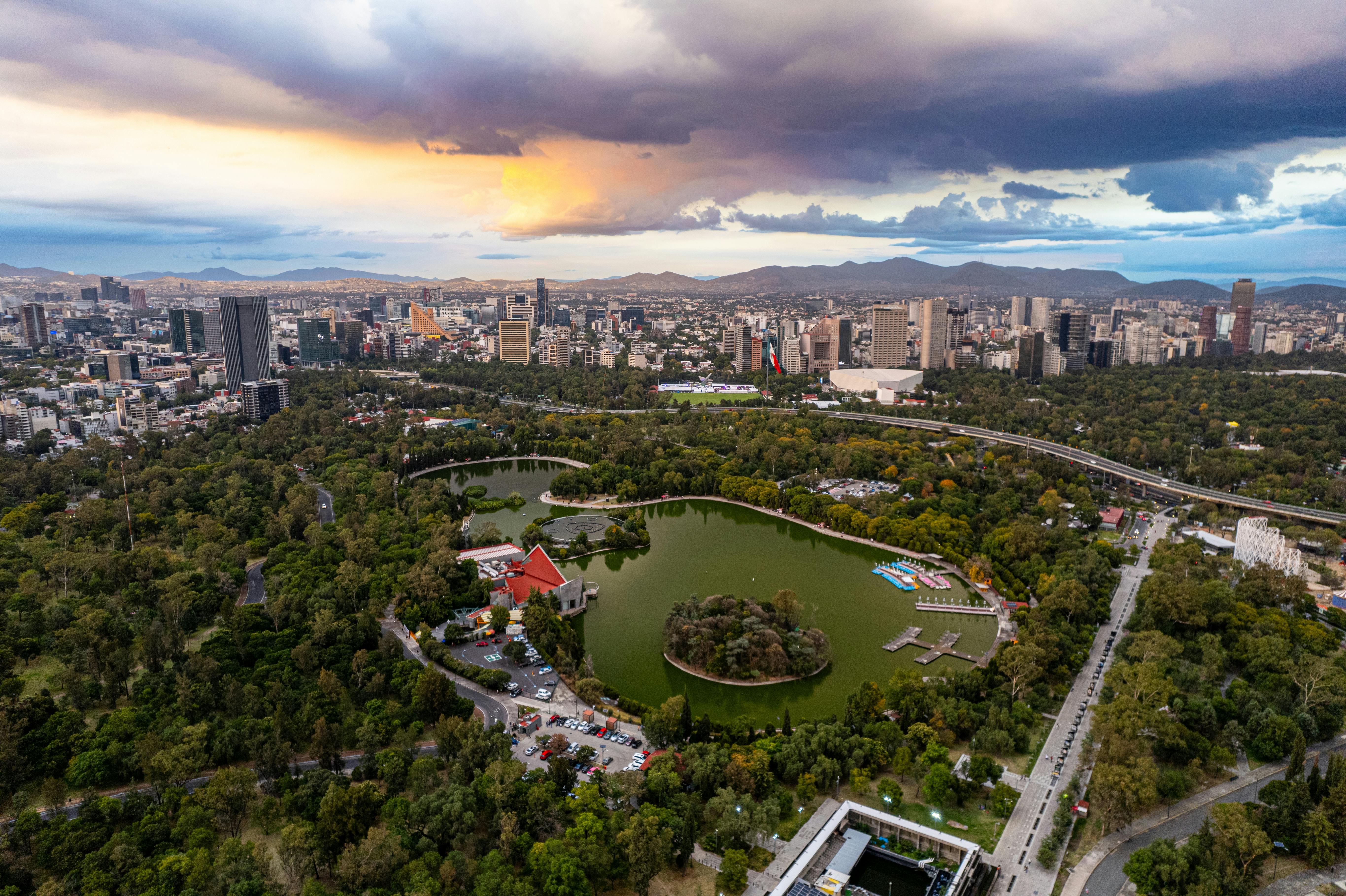 A large greenspace in Mexico City with a pond in the center of hundreds of lush, green trees