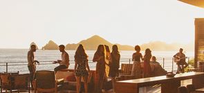 group of people on a deck off the ocean in los cabos in the sunset